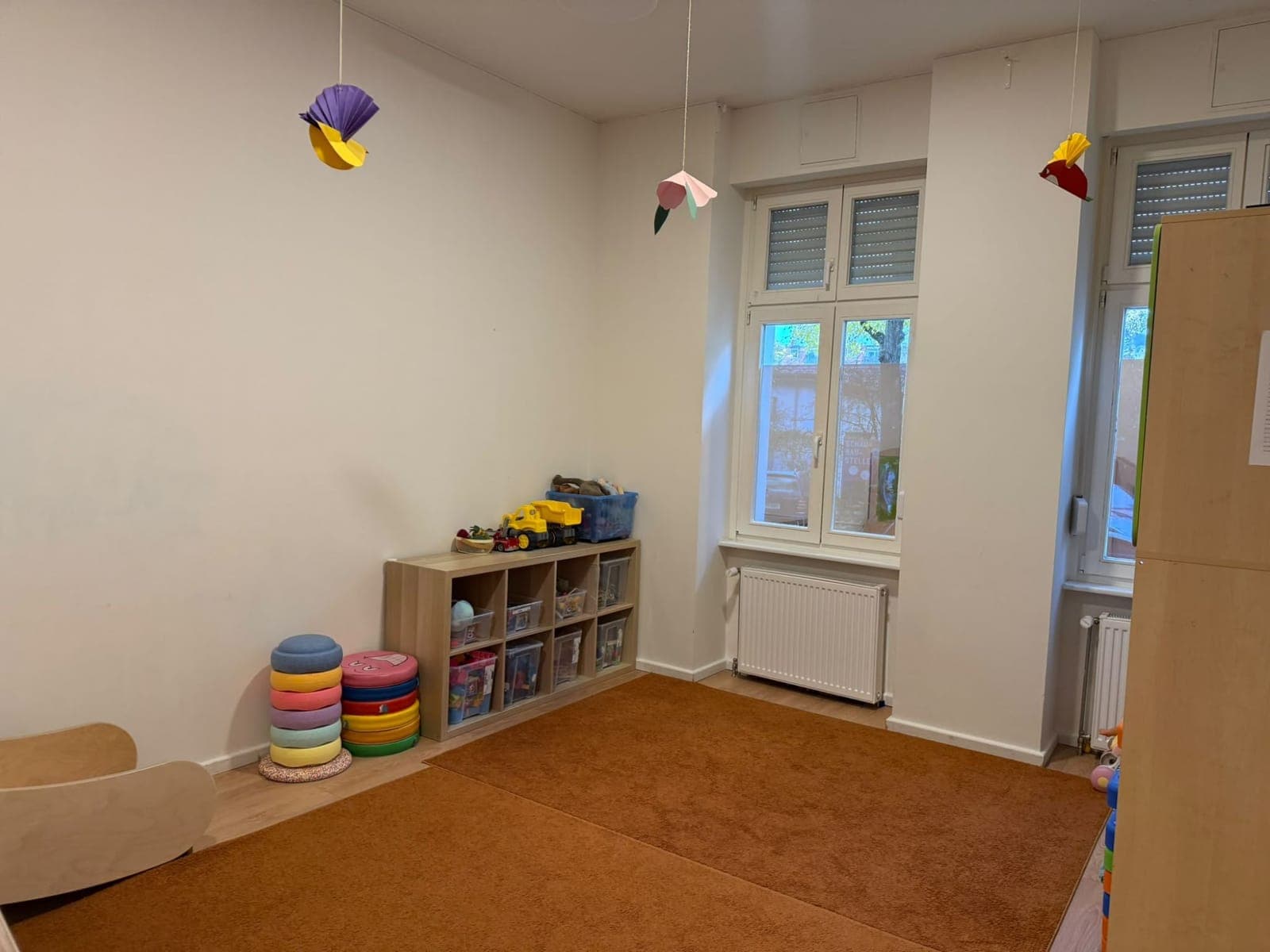 Heller Raum mit Teppich, Stapelsteinen und einem Regal voller Spielsachen